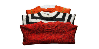 Tre vikta stickade tröjor i rött, svartvitt och orange ligger staplade på varandra mot vit bakgrund.