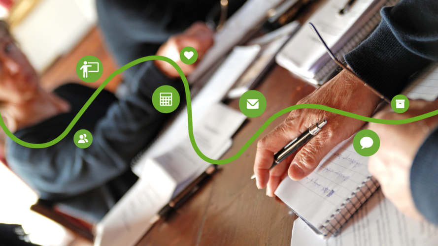 Personer skriver i anteckningsböcker vid ett bord, med gröna ikoner och en vågig linje ovanpå bilden.