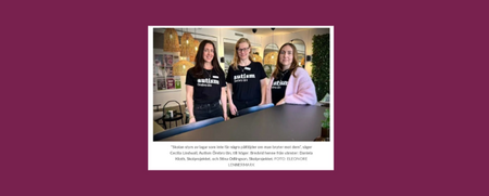 Fyra personer står vid ett bord inomhus, två bär svarta tröjor med texten 'autism awareness'.