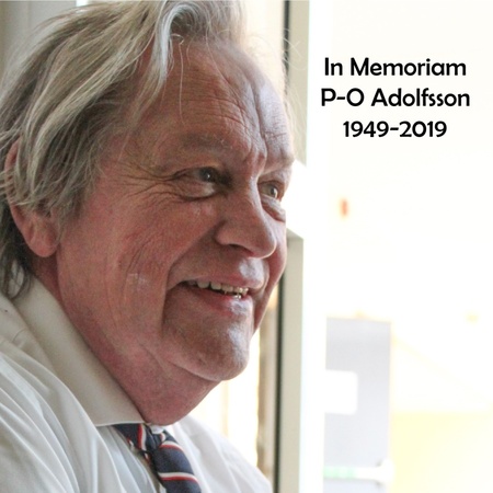 Äldre man i vit skjorta och slips ler, minnesband och texten 'In Memoriam P-O Adolfsson 1949–2019' syns i hörnet.
