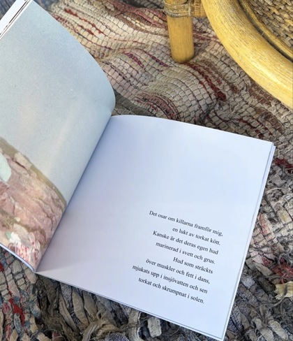 En öppen bok med svensk text ligger på en mönstrad matta bredvid en trästol.