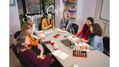 Sju kvinnor sitter runt ett bord och samtalar på ett språkcafé, med kaffe och choklad.
