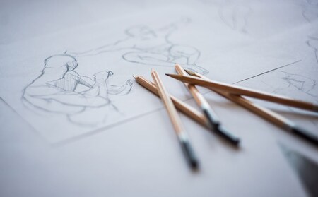 Fyra blyertspennor ligger på papper med skisser av mänskliga figurer i rörelse.