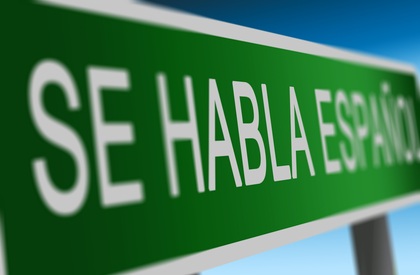 Grön skylt med vit text som säger 'SE HABLA ESPAÑOL' mot en blå bakgrund.