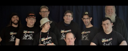 Gruppfoto på tio personer i svarta t-shirts framför en mörk bakgrund.