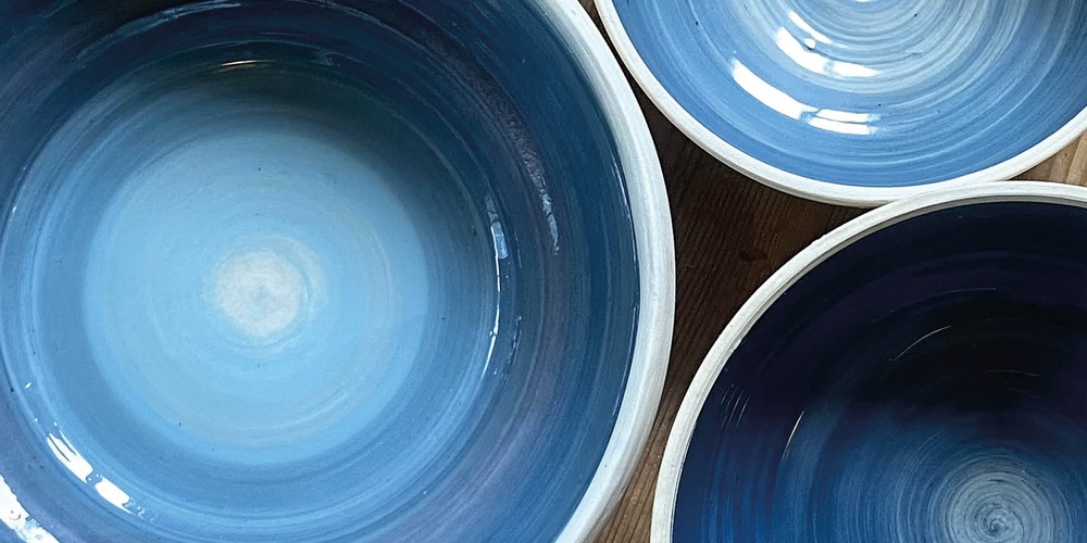 Tre blå keramikskålar på ett trägolv med texten 'Prova på: Keramik' i hörnet.