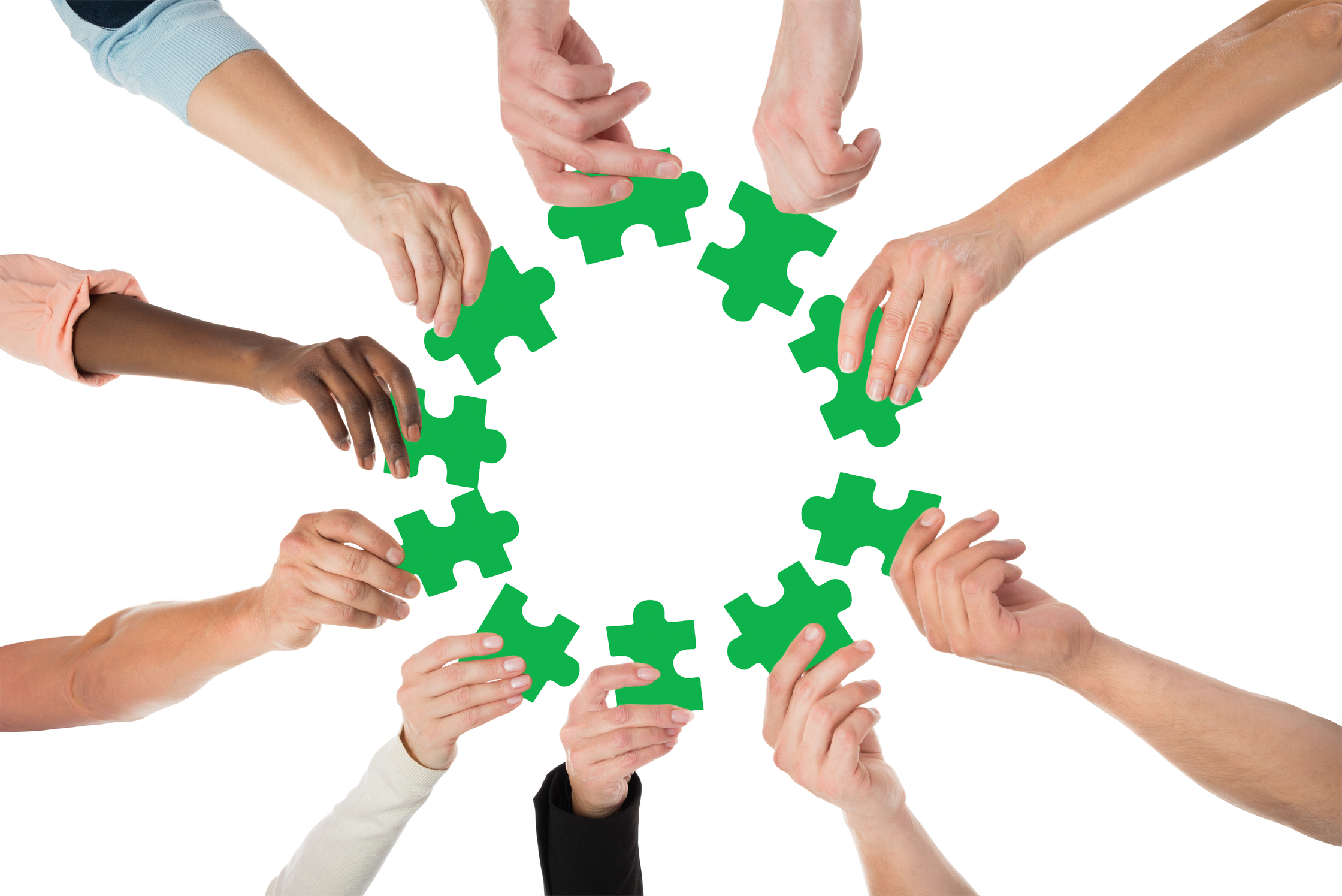 Flera händer håller gröna pusselbitar i en cirkel mot en vit bakgrund.