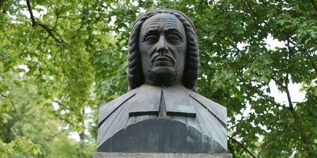 Byst av Olof Broman på en stenpelare i en grön park, med inskription på svenska.