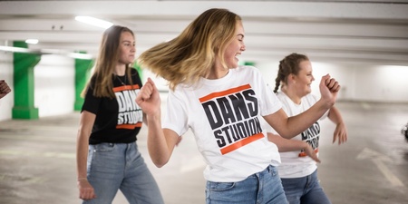 Tre dansare i parkeringsgarage i Dansstudion-tröjor