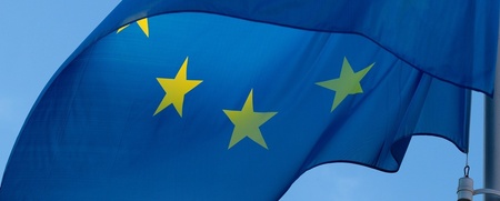 Europeiska unionens flagga med gula stjärnor på blå bakgrund vajar mot en klarblå himmel.