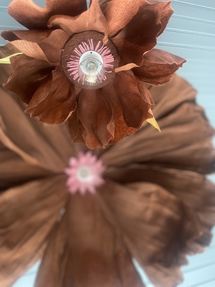 Två stora konstgjorda blommor i bruna nyanser med rosa mitt, fotograferade underifrån.