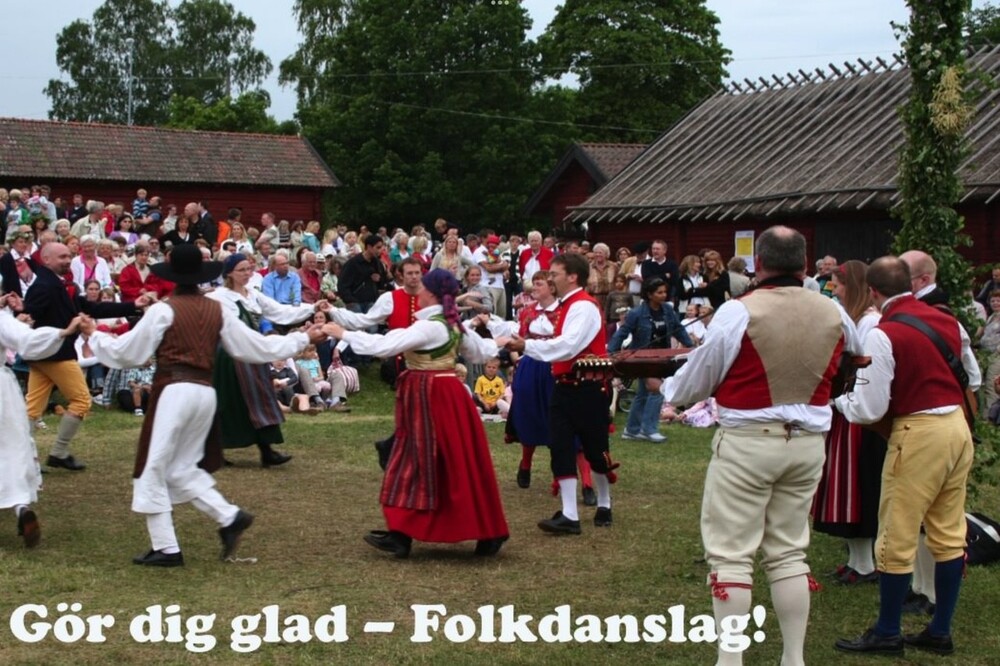 Människor i traditionella folkdräkter dansar i ring utomhus inför en publik.