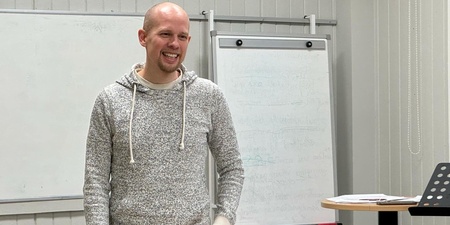 En person står i ett klassrum framför en whiteboard och ett blädderblock.