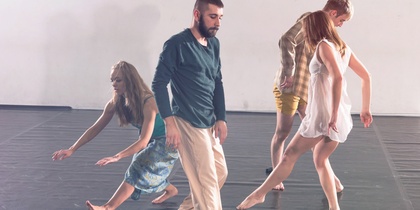 Fyra personer dansar barfota på ett svart golv i en ljus dansstudio.