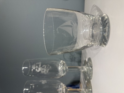 Tre glas står på ett vitt bord mot en grå bakgrund, ett av dem har ett segelbåtsmotiv.