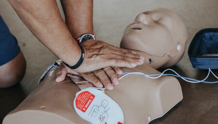Person utför hjärt-lungräddning på en docka med defibrillatorpads under en övning.