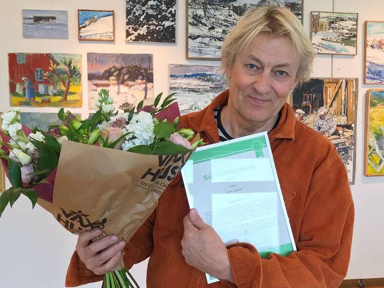 Lars Lerin med blommor och diplom i händerna.