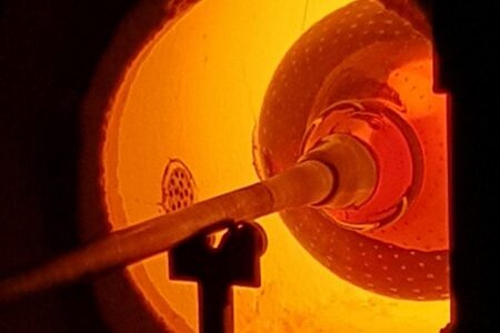 Ett glödande rör i en ugn med starkt orange ljus, troligen vid en industriell process.