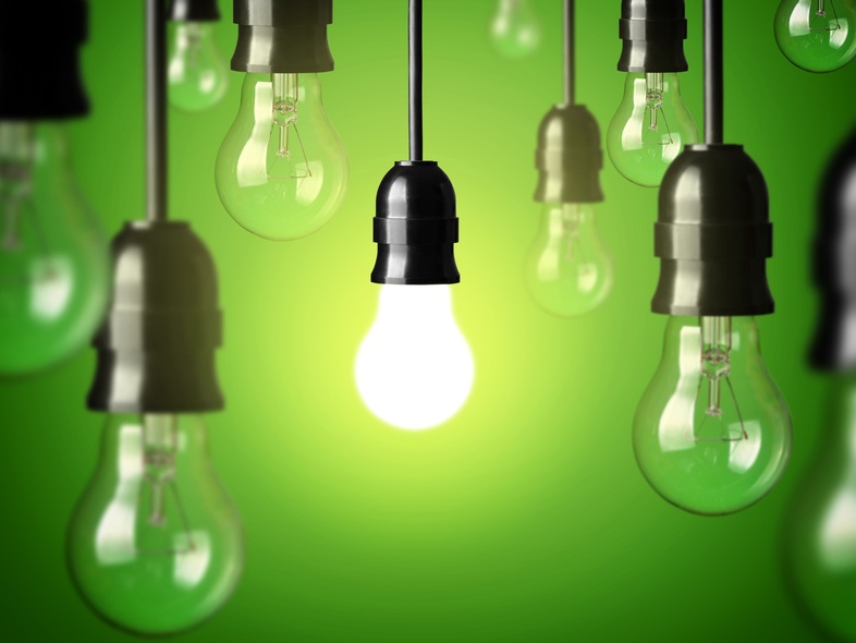 Flera hängande glödlampor mot grön bakgrund, en lampa lyser medan resten är släckta.