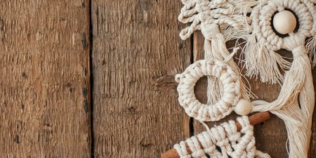 Makramé juldekorationer hänger på en rustik trävägg, inklusive gran, krans och geometriska former.