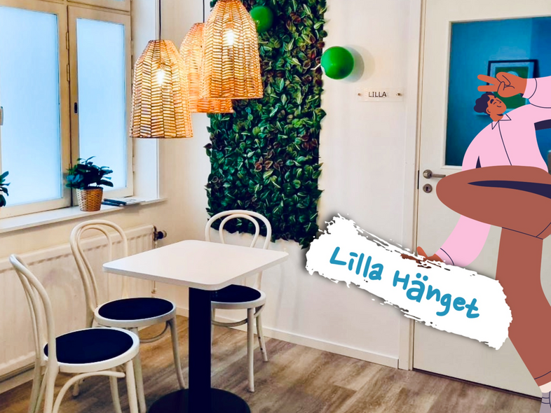 Litet café med vita stolar, bord, växtvägg, rottinglampor och tecknad figur med skylten 'Lilla Hänget'.