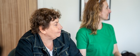 Två kvinnor sitter vid ett bord och antecknar under ett möte eller en workshop.