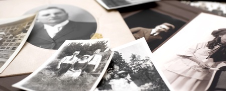 En hög med gamla svartvita fotografier, flera visar människor och familjer utomhus och inomhus.