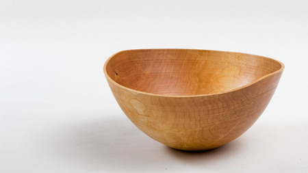 En handgjord träskål med naturlig finish står på en vit bakgrund.