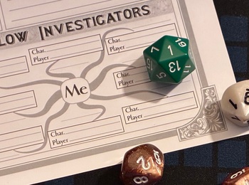 Flera tärningar och ett rollformulär för rollspel ligger på ett rutigt spelbord.