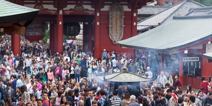 Stor folkmassa samlad vid ett tempel i Japan, med rök från en rökelsebrännare i förgrunden.