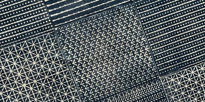 Ett mörkblått och vitt tyg indelat i rutor med olika handtryckta geometriska mönster i japanskinspirerad stil