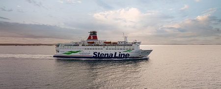En Stena Line-färja seglar på ett lugnt hav under en molnig himmel vid solnedgång.