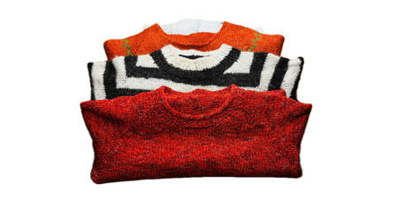 Tre vikta stickade tröjor i rött, svartvitt och orange ligger staplade på varandra mot vit bakgrund.