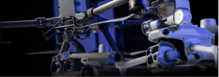 Närbild av två avancerade drönare med kameror och sensorer i blå belysning.