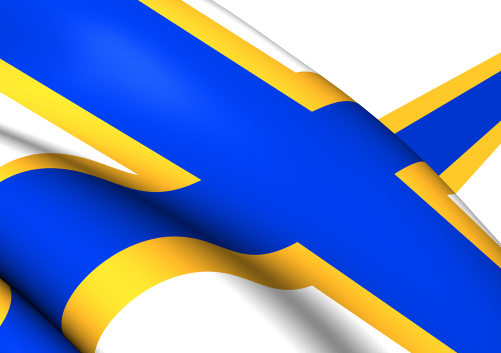 Närbild av en blå och gul flagga med korsmönster, troligen Sveriges flagga, som vajar i vinden.