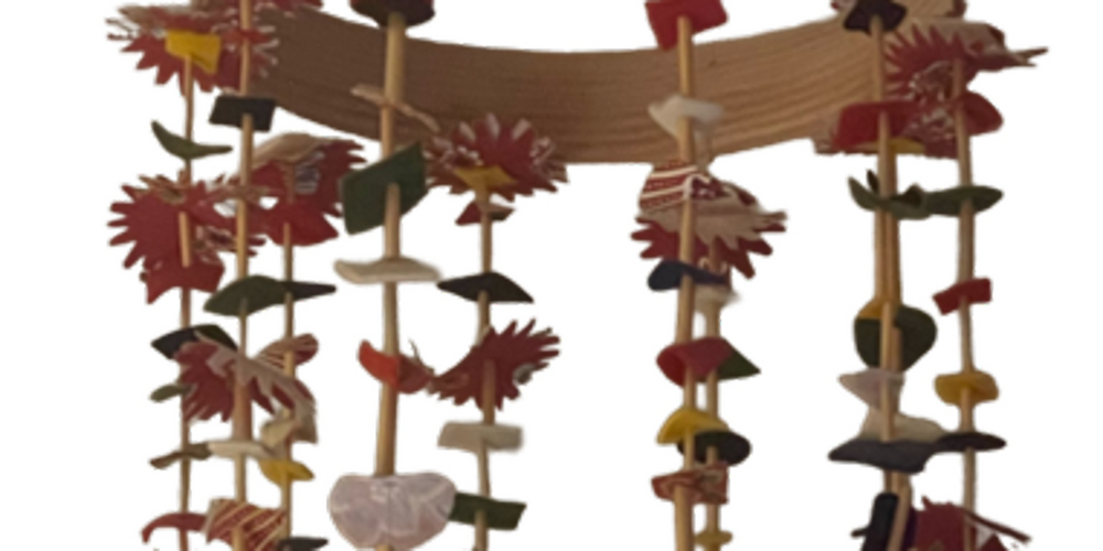 En mobil av halm och tyg i olika färger, hängande från en rund träram.