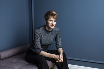 Person sitter på en bänk i ett rum med blå väggar och håller händerna i knät.