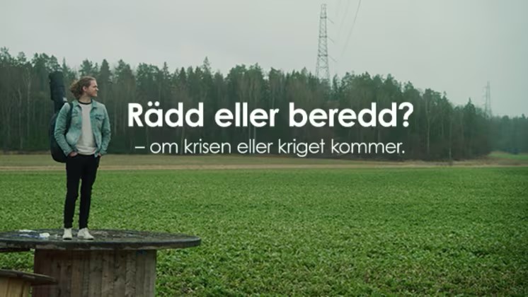 En person står på en träplattform på ett fält med skog i bakgrunden och texten 'Rädd eller beredd?'.