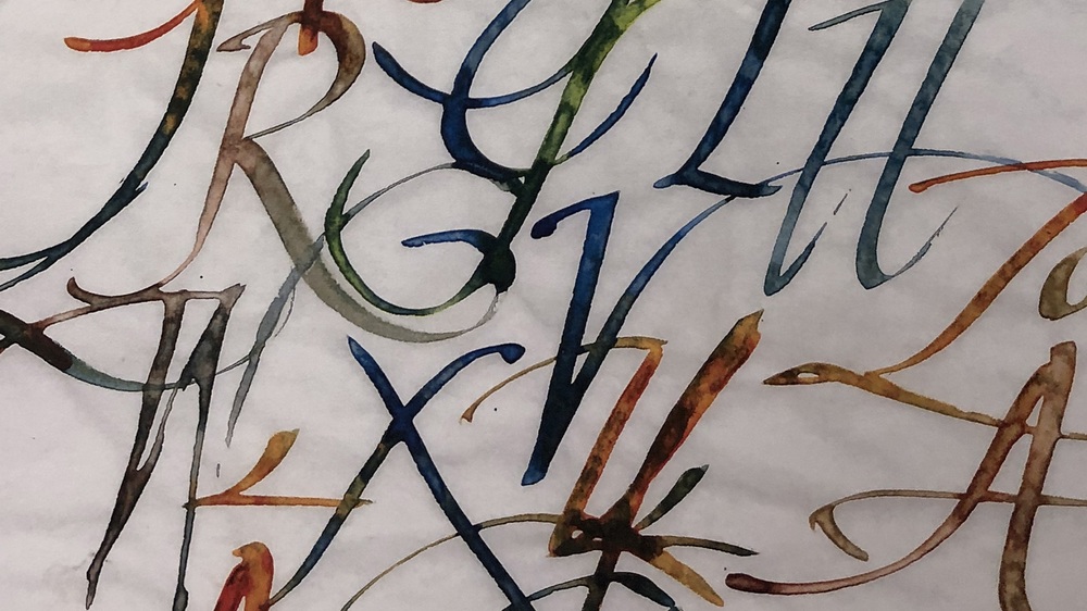 Färgglad kalligrafi med stora, snirkliga bokstäver på vitt papper.