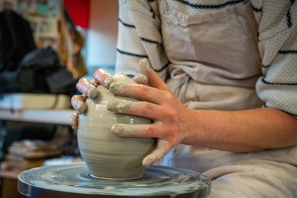 En person formar lera på en drejskiva i en keramikverkstad.