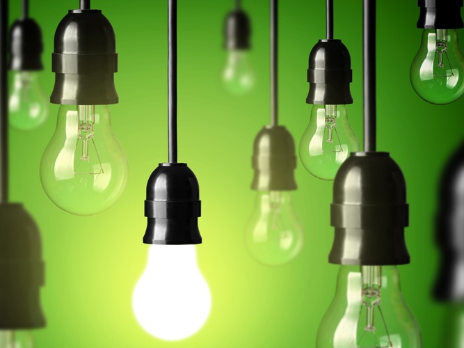 Flera hängande glödlampor mot grön bakgrund, en lampa lyser medan resten är släckta.