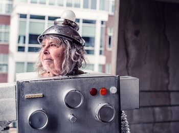 Person utklädd till robot med kartong och hushållsartiklar, står i en urban miljö.