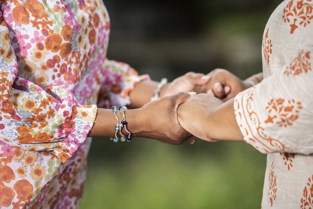 Två personer håller varandra i händerna utomhus, båda bär blommiga kläder.
