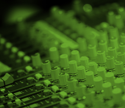 Närbild av ett ljudmixerbord med många reglage och rattar, belyst i grönt ljus.