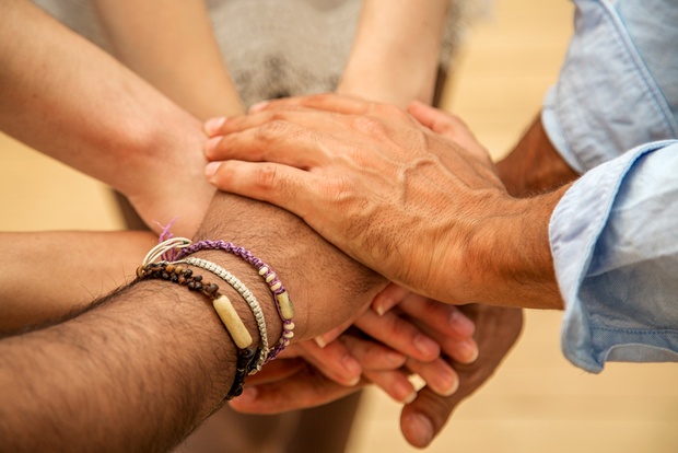 Flera händer lagda ovanpå varandra i en gest av samarbete och gemenskap.