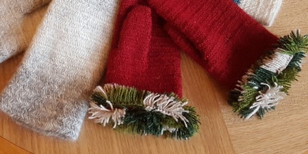 Fyra par stickade vantar i olika färger ligger på ett trägolv.