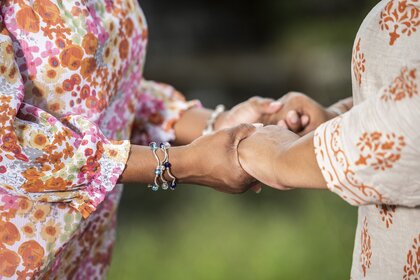 Två personer håller varandra i händerna utomhus, båda bär blommiga kläder.