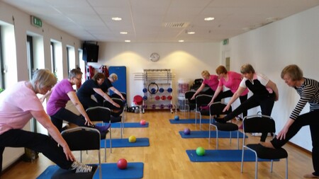 En grupp människor är i ett rum och har stolsyoga.