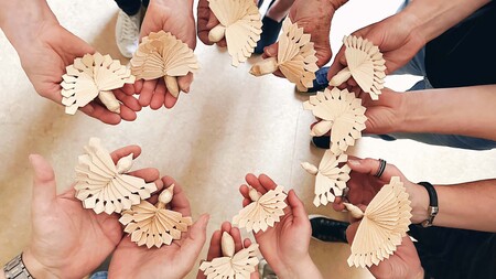 Flera händer håller träfåglar i en cirkel, fotograferat uppifrån.