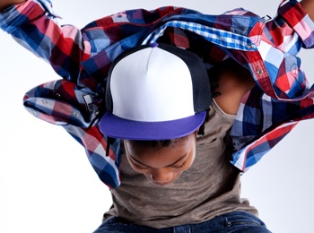 Person i jeans och rutig skjorta hoppar med armar och ben utsträckta mot en ljus bakgrund.